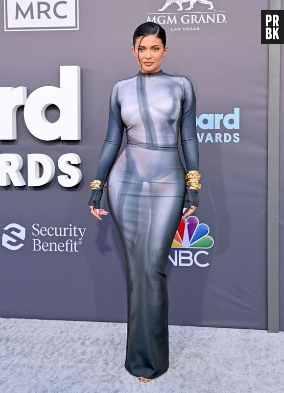 Kylie Jenner investiu em um vestido justo em um tom cinza frio, combinando com pulseira de ouro e saltos todos da Balmain, no Billboard Music Awards 2022