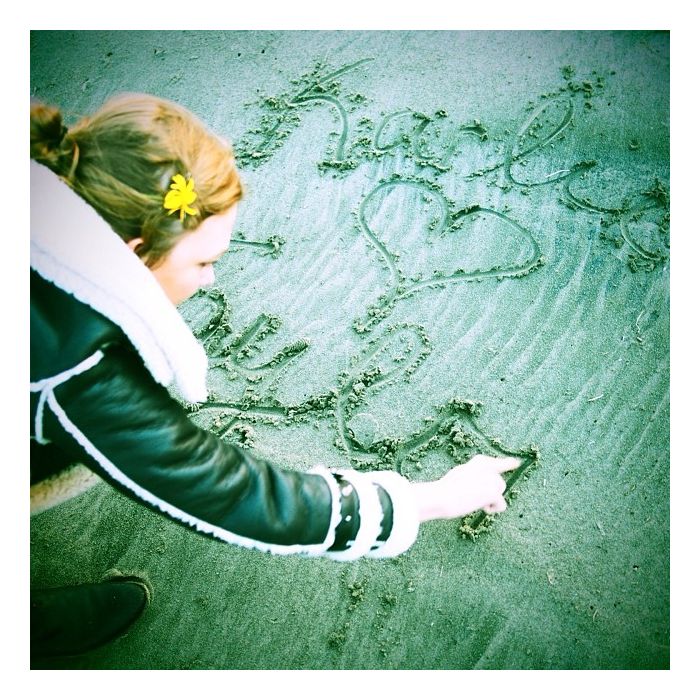 Karlie Kloss grava na areia seu nome e da amiga Taylor Swift