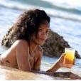 Em Barbados, Rihanna curte praia com copo de bebida na mão
