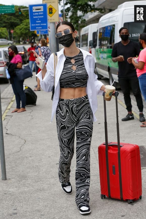 A atriz Vitória Strada combina conjunto de cropped e calça estampada em aeroporto