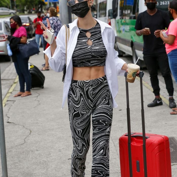 A atriz Vitória Strada combina conjunto de cropped e calça estampada em aeroporto