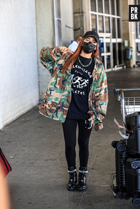 Anitta combina look all black com maxi casaco com estampa militar em aeroporto