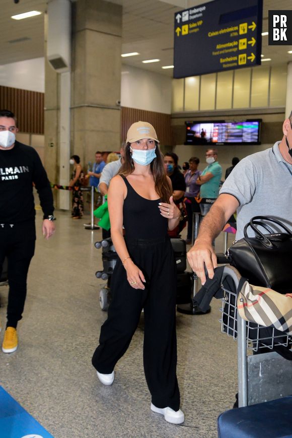 Isis Valverde combina regata preta com calça sporty e boné em aeroporto