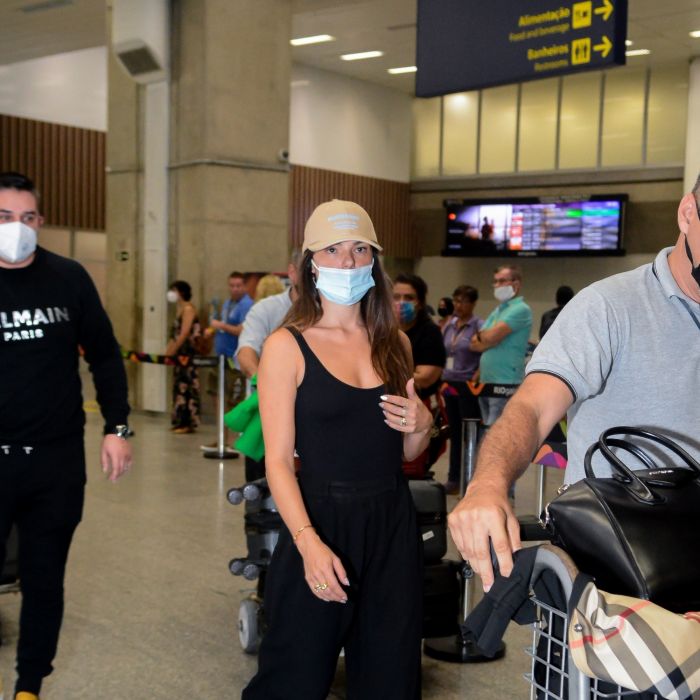 Isis Valverde combina regata preta com calça sporty e boné em aeroporto