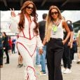 Ludmilla perfeita com macacão branco e vermelho ao lado de Brunna Gonçalves de calça e blusinha no GP de F1