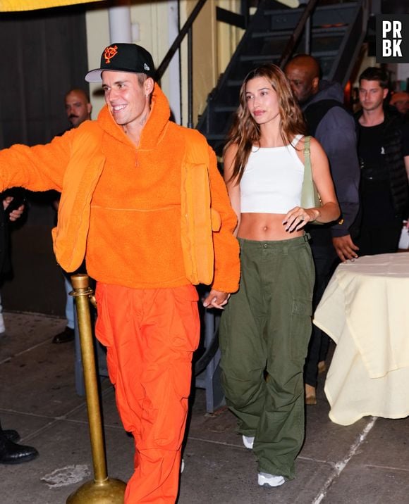 Hailey Bieber com um look mais casual e Justin com um look totalmente laranja