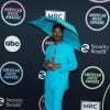 Billy Porter  usou um chapéu de chuva combinando com seu terno azul, ambos acervos da marca Botter