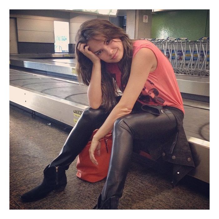 A atriz Lua Blanco se diverte sentada na esteira do aeroporto