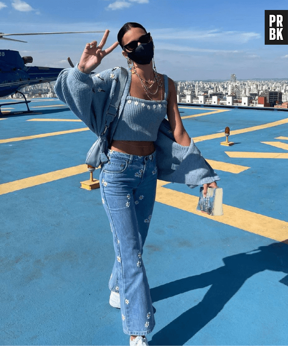 Bruna Marquezine forma look estilo kidcore: cropped, jeans, cardigã e um tênis flat branco.