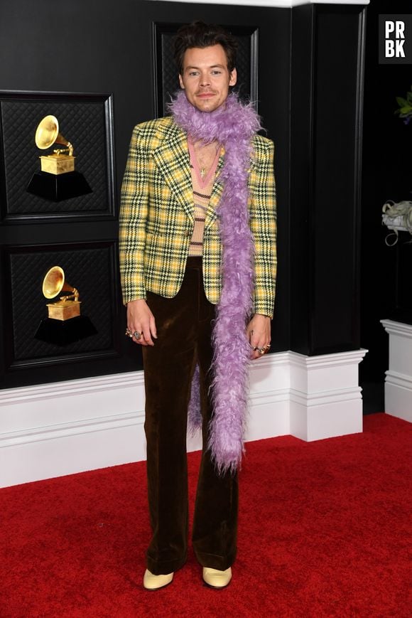 Contrariando o público, Harry Styles apareceu com dois ternos no Grammy Awards 2021. Um deles preto e de couro e outro um blazer xadrez amarelo. Os dois foram complementados com encharpes de plumas coloridas