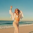 Larissa Manoela combina biquíni de textura branco com calça de renda ao rir à praia