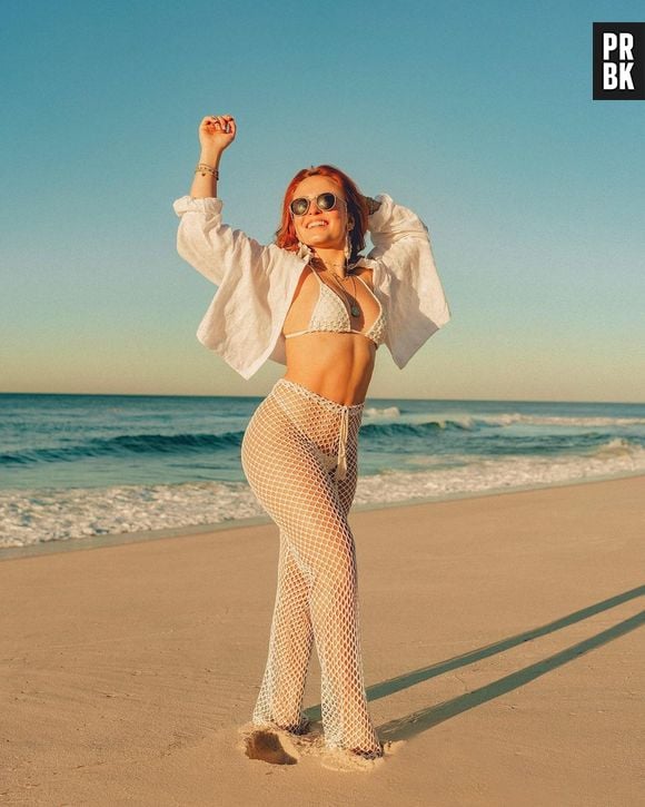 Larissa Manoela combina biquíni de textura branco com calça de renda ao rir à praia